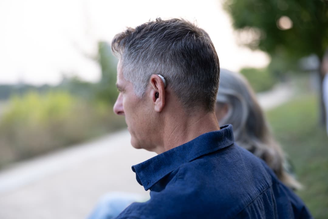 Man wears hearing aids looking into the horizon