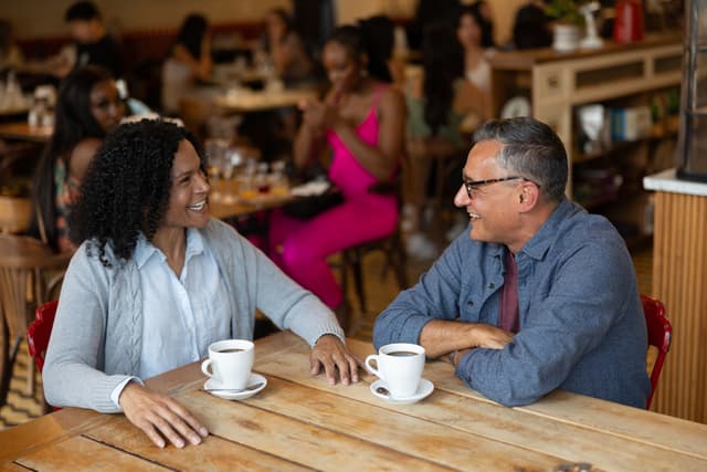 man and woman drinking coffee with hearing aids in ear