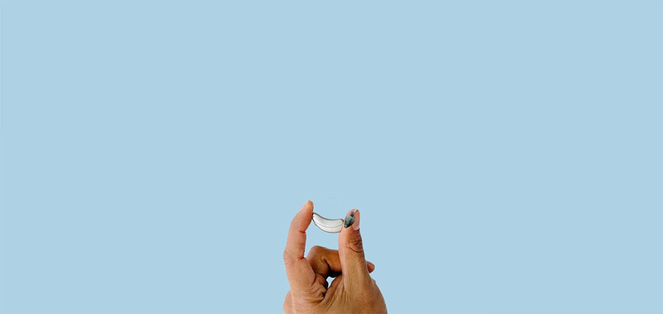 hand holding hearing aid over blue background