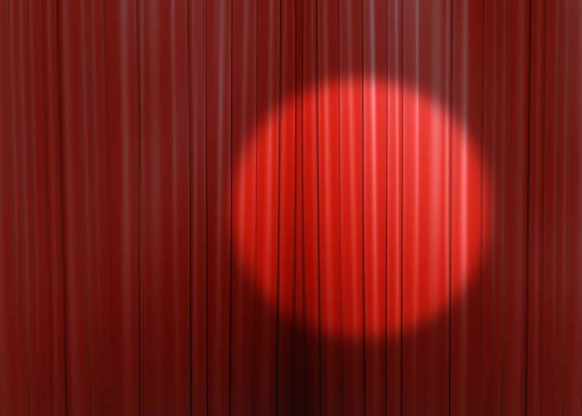 Stage with spotlight shining over red curtain