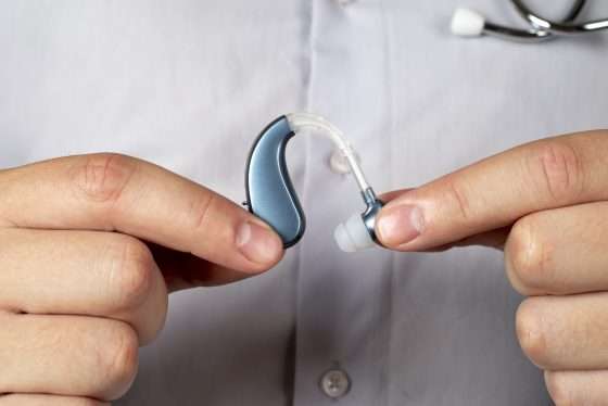 Hands holding blue-grey hearing aids