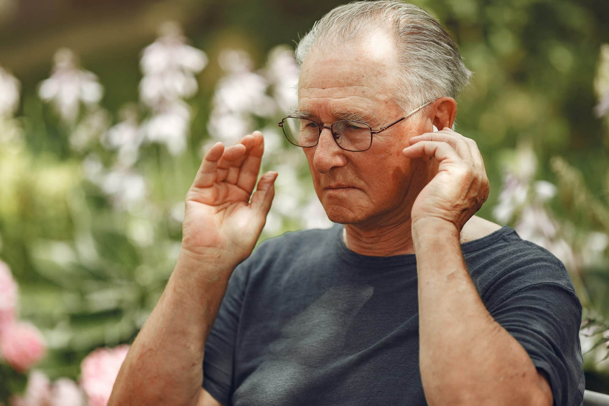 older man adjusting his philips hearing aid